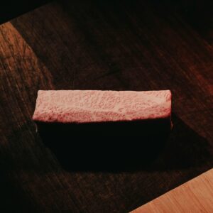 Close-up of marbled Wagyu beef on a rustic dark wooden table, showcasing rich texture and color contrast.